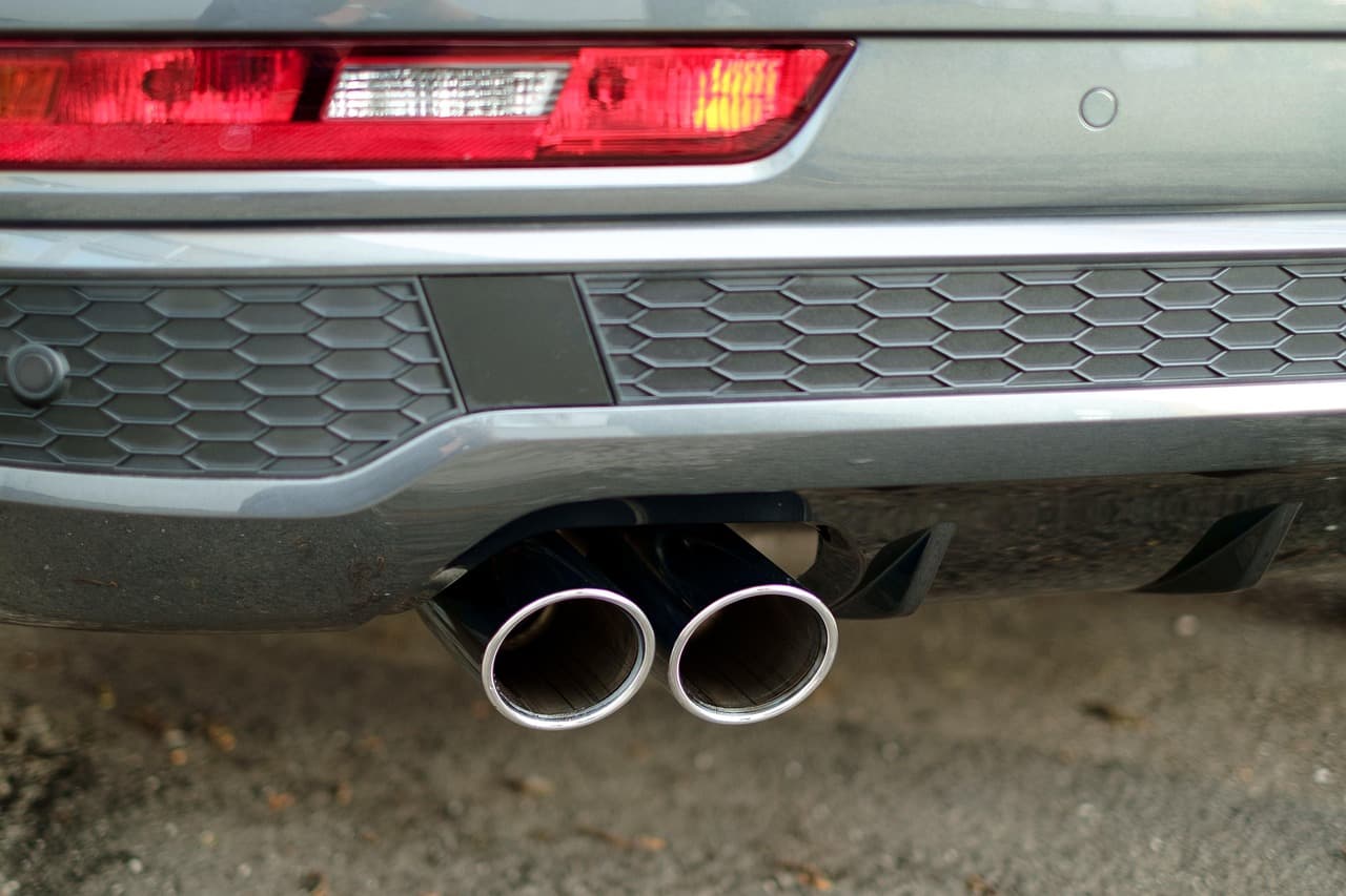 Twin stainless tailpipes under the rear bumper of a silver car