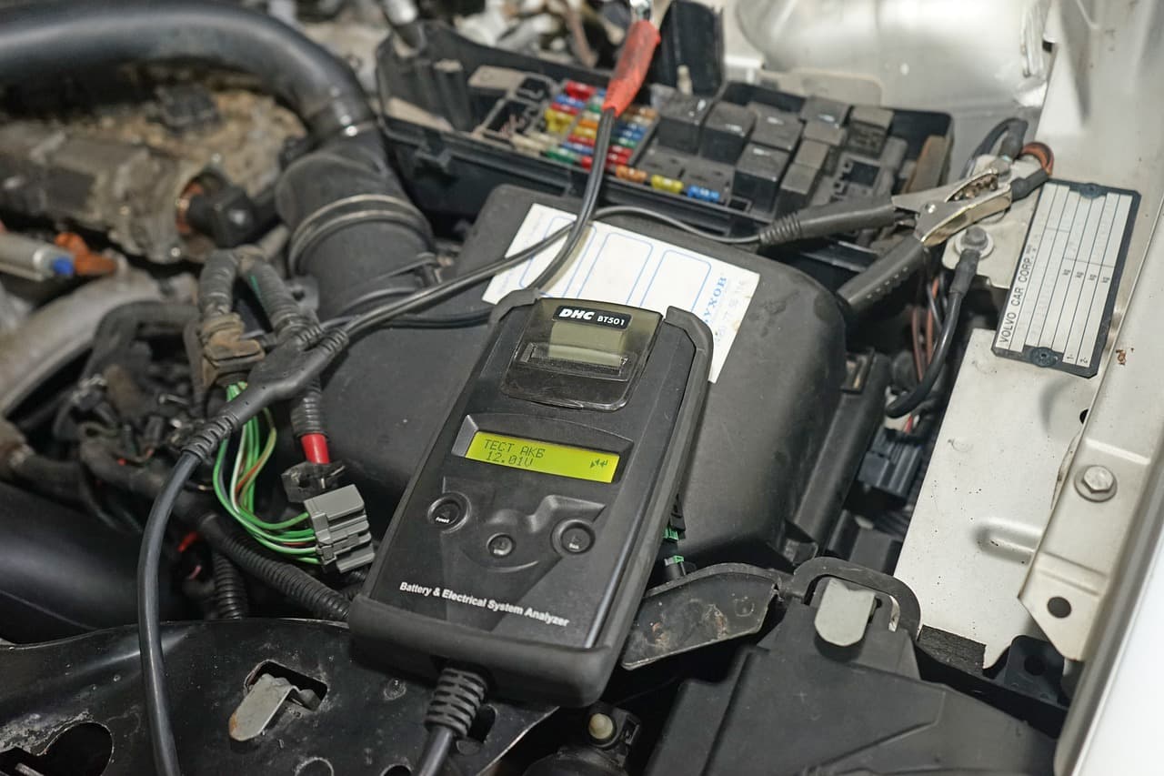 A battery and charging analyser clipped on in an open engine bay